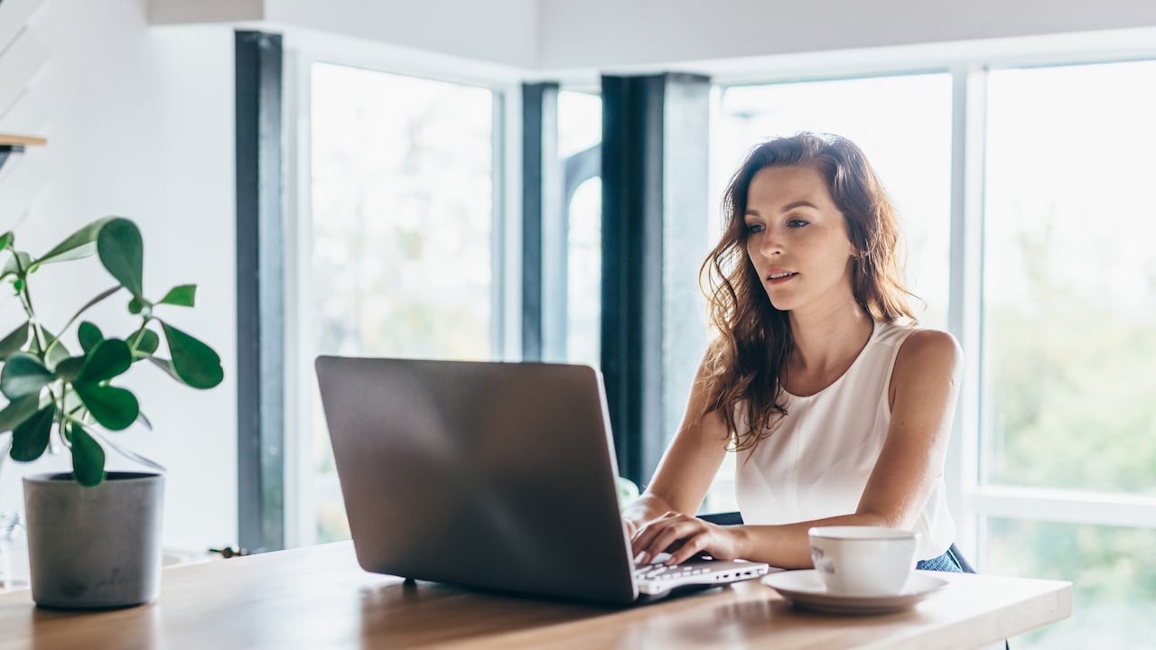 Mujer usando laptop mientras está sentado en casa. Mujer con computador portátil trabajando, trabajo virtual.
